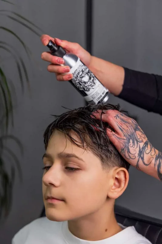 Applying Scissor Hands Liquid Wax to damp children’s hair to create texture
